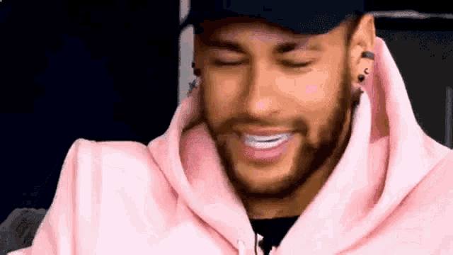 a close up of a man wearing a pink hoodie and a hat .