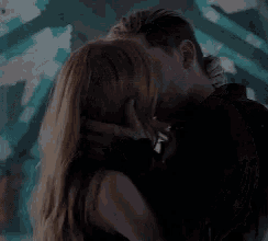 a man and a woman are kissing in front of a painting .