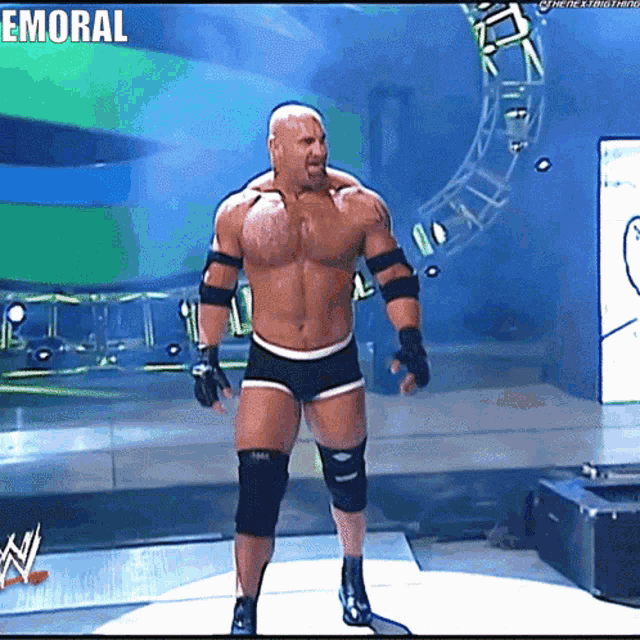 a shirtless wrestler is standing on a stage with the word emoral written above him