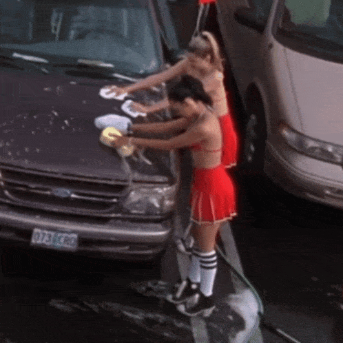 two cheerleaders are washing a ford van with a license plate that says 073 vcro