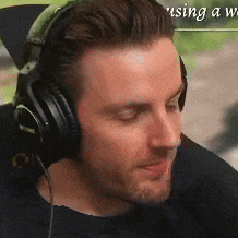 a man wearing headphones is sitting in front of a sign that says using a web .