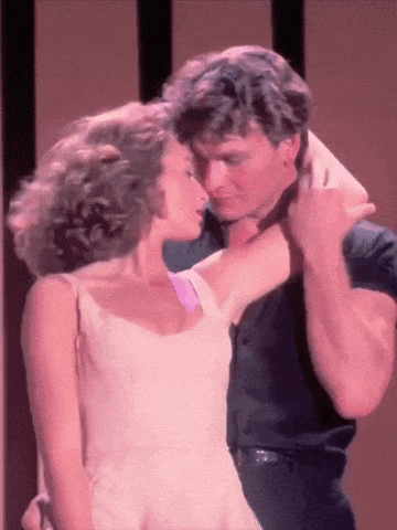 a man and a woman are dancing together and the woman is wearing a pink dress
