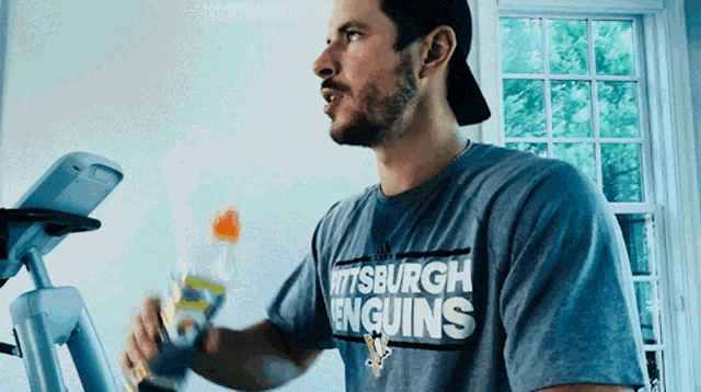 a man wearing a pittsburgh penguins shirt holds a bottle of gatorade