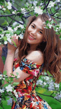 a woman in a floral dress smiles while standing under a tree with white flowers