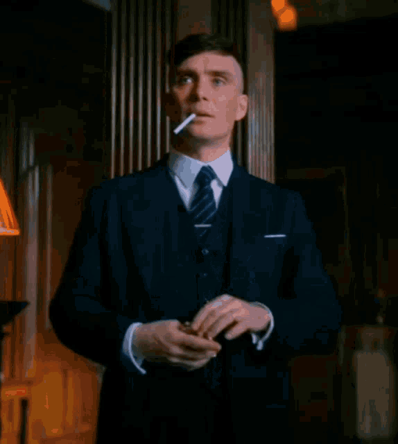 a man in a suit is smoking a cigarette .