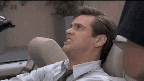a man in a suit and tie is sitting in a dental chair and making a funny face .