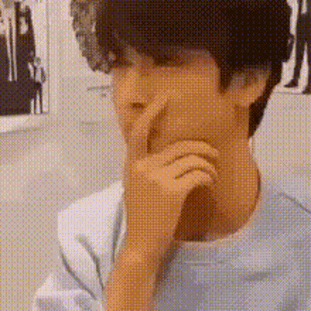 a close up of a person covering their face with their hand