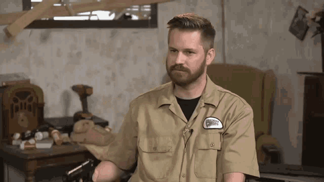 a man wearing a khaki shirt with a patch on his chest that says ' pilot ' on it