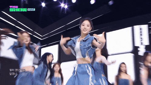 a group of women are dancing on a stage with the words the show visible in the background