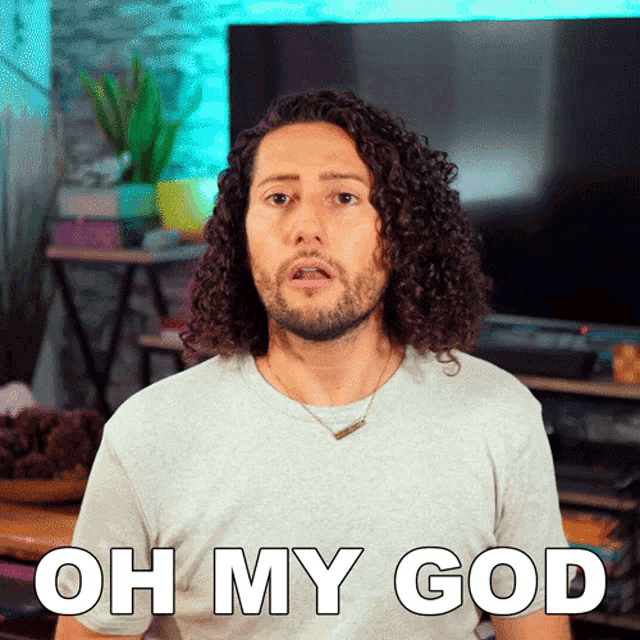a man with curly hair says oh my god in front of a television