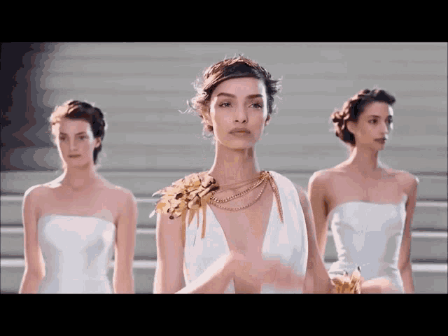 a woman in a white dress with gold flowers on her shoulders