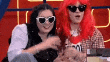 a woman with red hair and sunglasses is standing next to a man with red hair and sunglasses .