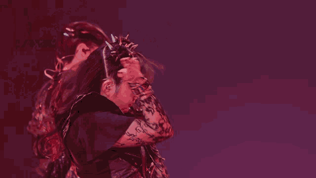 a woman with spikes in her hair is dancing in a dark room