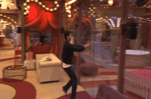 a man is dancing in a room with a red curtain behind him