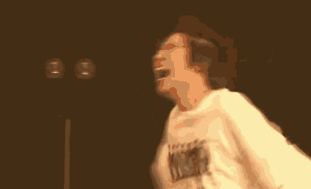 a man in a white shirt is dancing with his arms outstretched in a blurry photo .