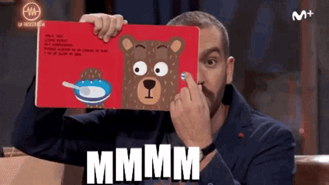 a man holding a book with a teddy bear on it and the word mmmm on the bottom