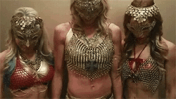 three women wearing masks are standing next to each other in a room .