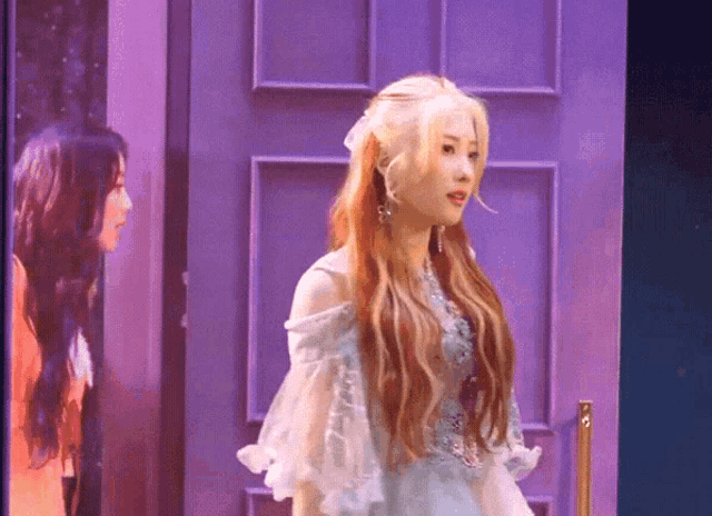 a woman in a white dress stands in front of a purple door