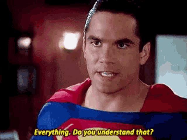 a man in a superman costume is talking to another man in a living room .