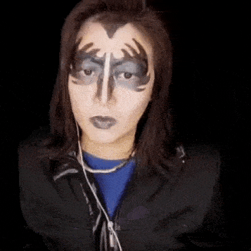 a woman with face paint on her face is wearing headphones and holding a knife .
