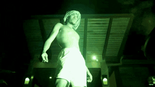 a man without a shirt is standing in the dark