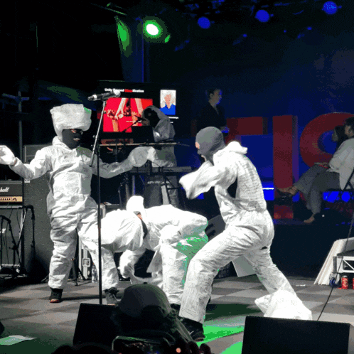 a marshall amplifier is behind a group of people in white jumpsuits