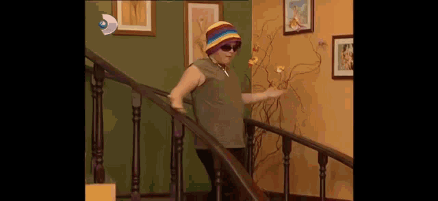 a woman wearing a hat and sunglasses is walking down a set of stairs