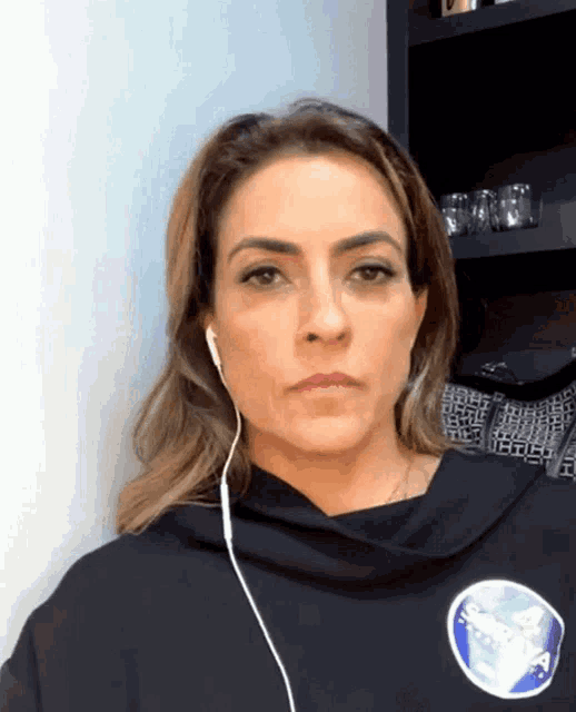 a woman wearing headphones and a nasa sweatshirt looks at the camera