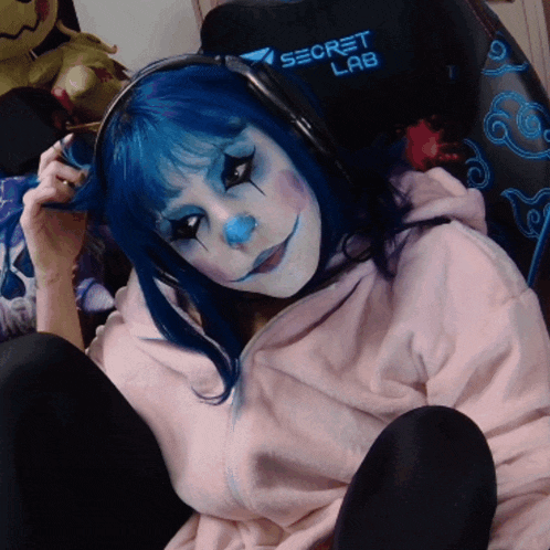 a girl with blue hair is sitting in a chair that says secret lab on it
