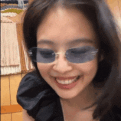 a woman wearing sunglasses is smiling and wearing a black shirt .