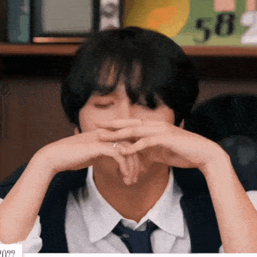 a man with a ring on his finger is covering his mouth with his hands