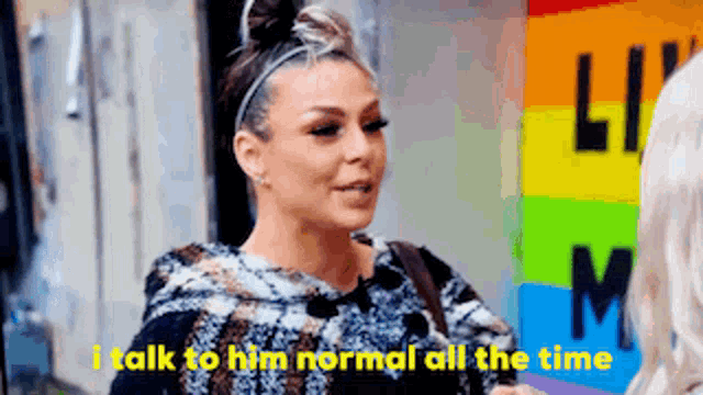 a woman says i talk to him normal all the time in front of a rainbow sign