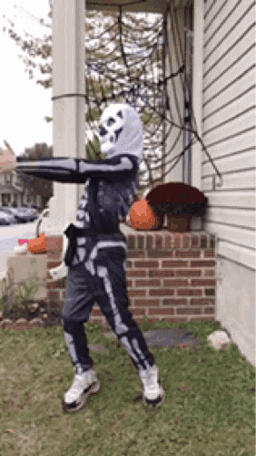 a person dressed in a skeleton costume is standing in front of a house .