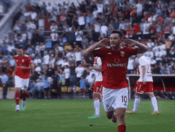 a soccer player in a red and white uniform is running on the field and celebrating a goal .