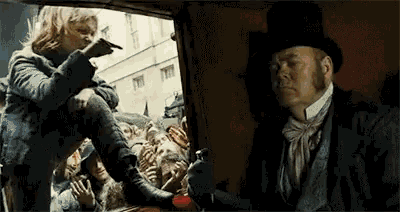 a man in a top hat is standing next to a woman in a stroller .