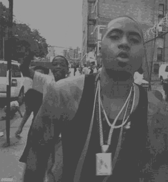 a black and white photo of a man in a tank top standing on a street .