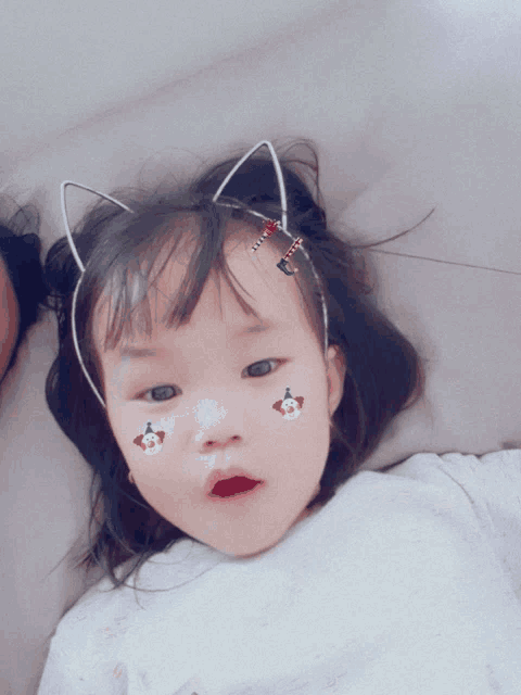 a little girl wearing a cat ear headband has stickers on her face