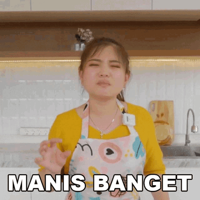 a woman in an apron is making a funny face and says manis banget