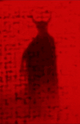 a shadow of a devil with horns is against a red wall