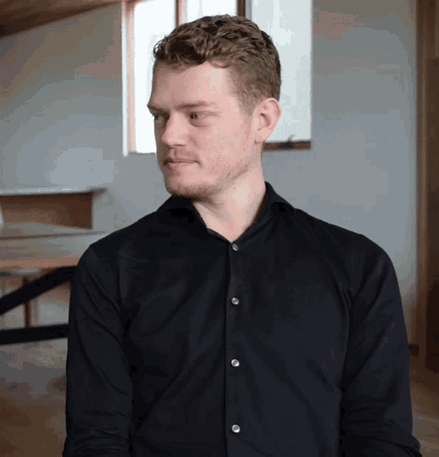 a man in a black shirt is looking to his left