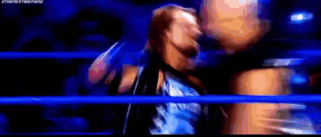 a man is wrestling another man in a wrestling ring while holding a knife .