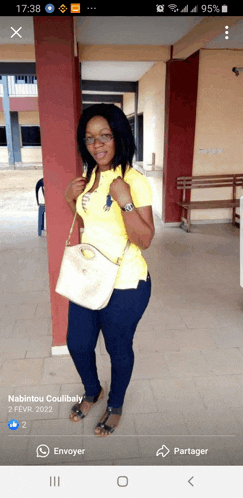 a woman in a yellow shirt and blue jeans is standing next to a pillar