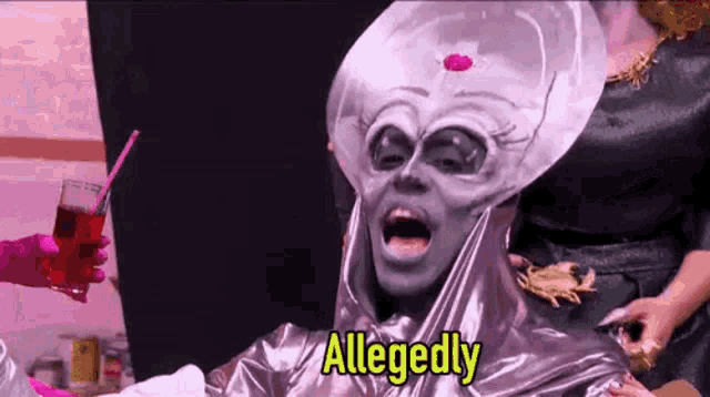 a drag queen dressed as an alien is holding a drink and a straw .