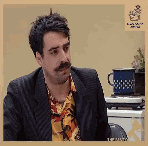 a man with a mustache is sitting in front of a cup that says the best of silovnik