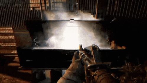 a person is holding a gun in a dark room with smoke coming out of it