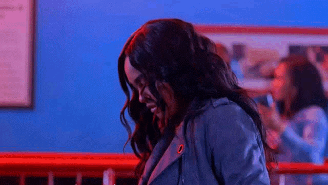 a woman in a leather jacket is standing in front of a red railing in a dark room .