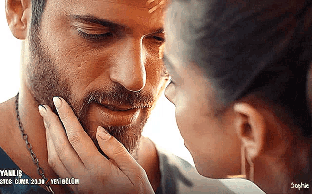 a close up of a woman touching a man 's face with yanlis written in the corner