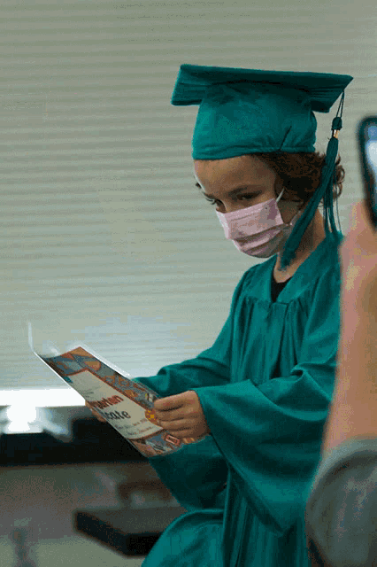 a girl wearing a graduation cap and gown is holding a certificate that says ' congratulations '