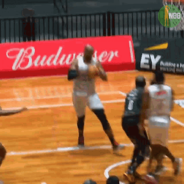 basketball players on a court with a budweiser banner in the background