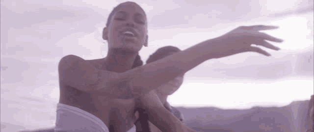 a woman in a white top is standing next to another woman with her arms outstretched